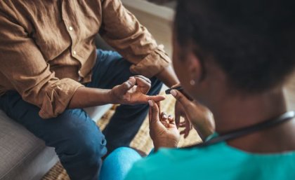 Woman taking blood sugar level of patient